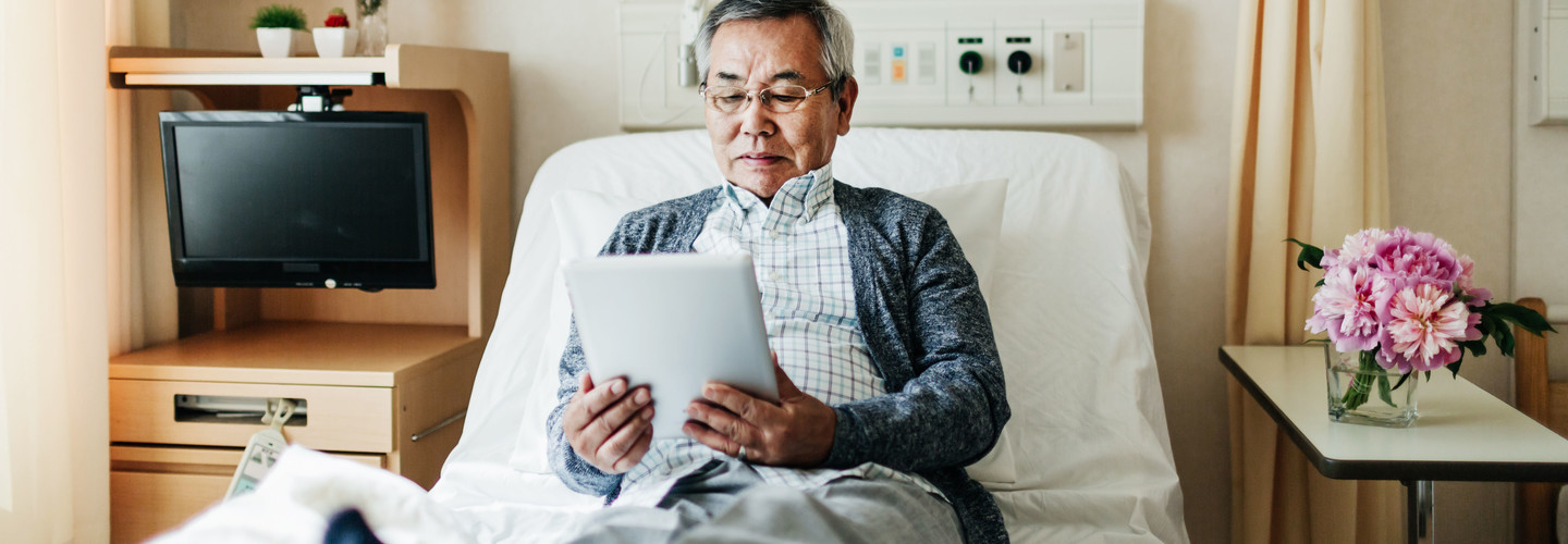 Man Reading on iPad in Hospital Room