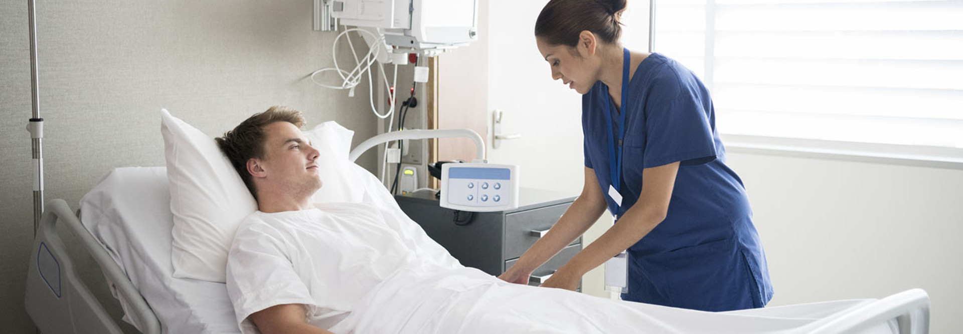 Young man in hospital bed with nurse by his side