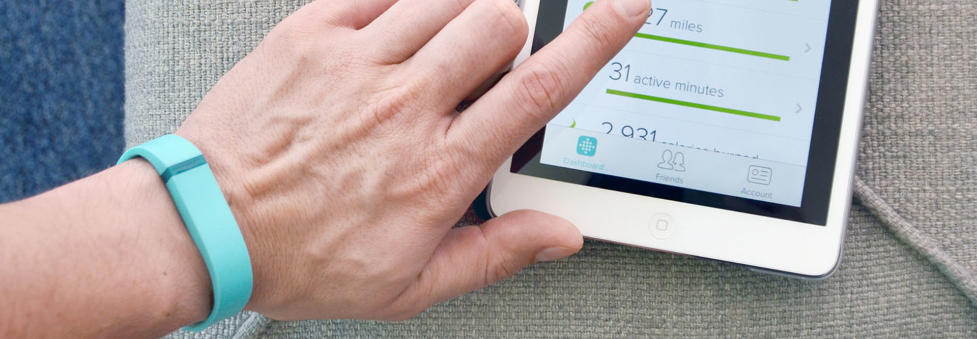 Close up of a man wearing a Fitbit Flex using the App on an iPad Mini