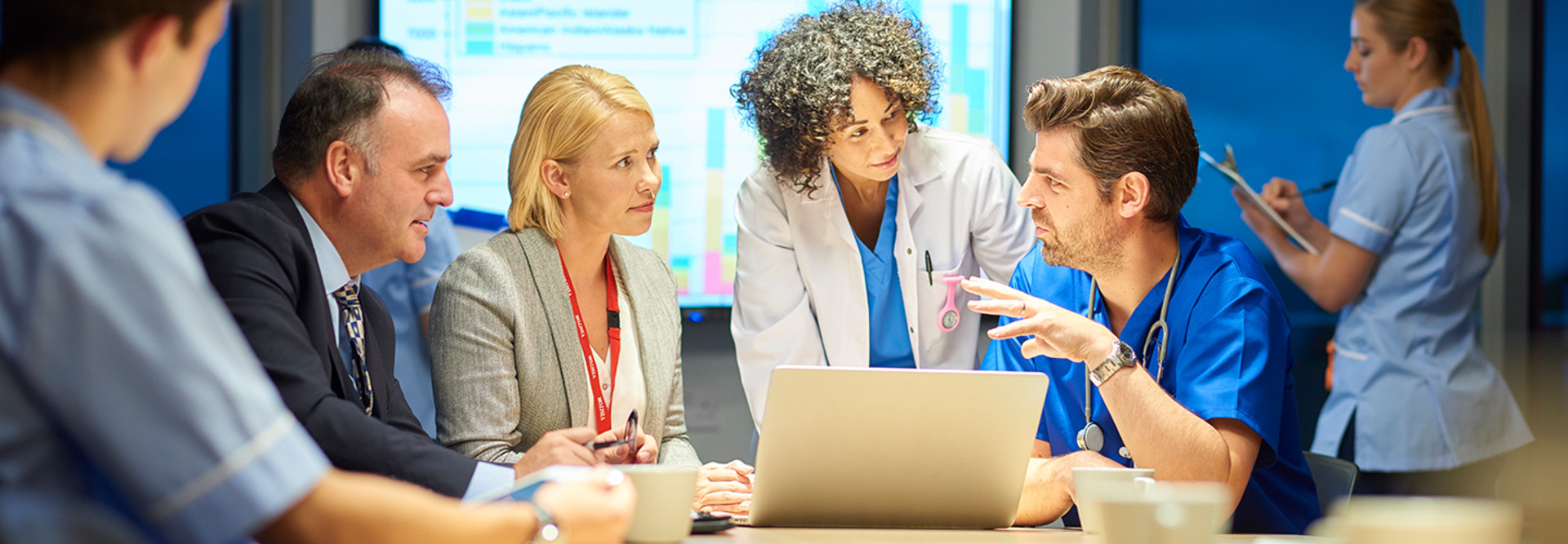 Doctors and business teams collaborating around computer