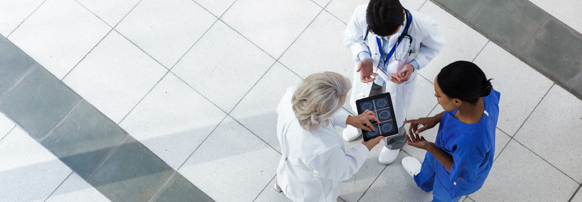 Hospital staff discussing patient care. The Doctors are using a digital tablet with the patient's chart.