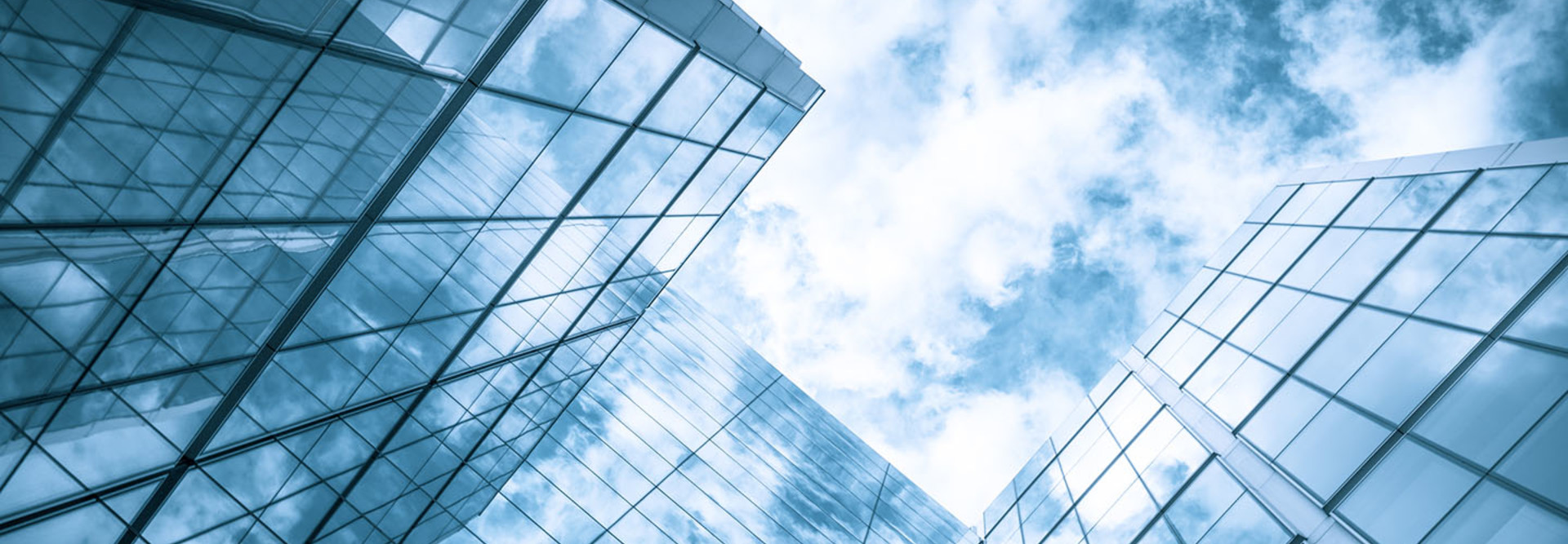 view of a contemporary glass skyscraper reflecting the blue sky and clouds