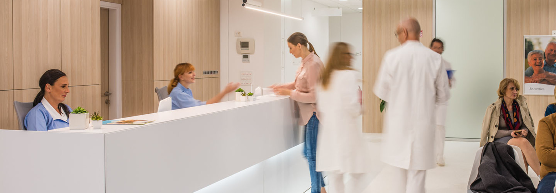 Blurred motion of doctors walking in clinic, patients sitting on chair.