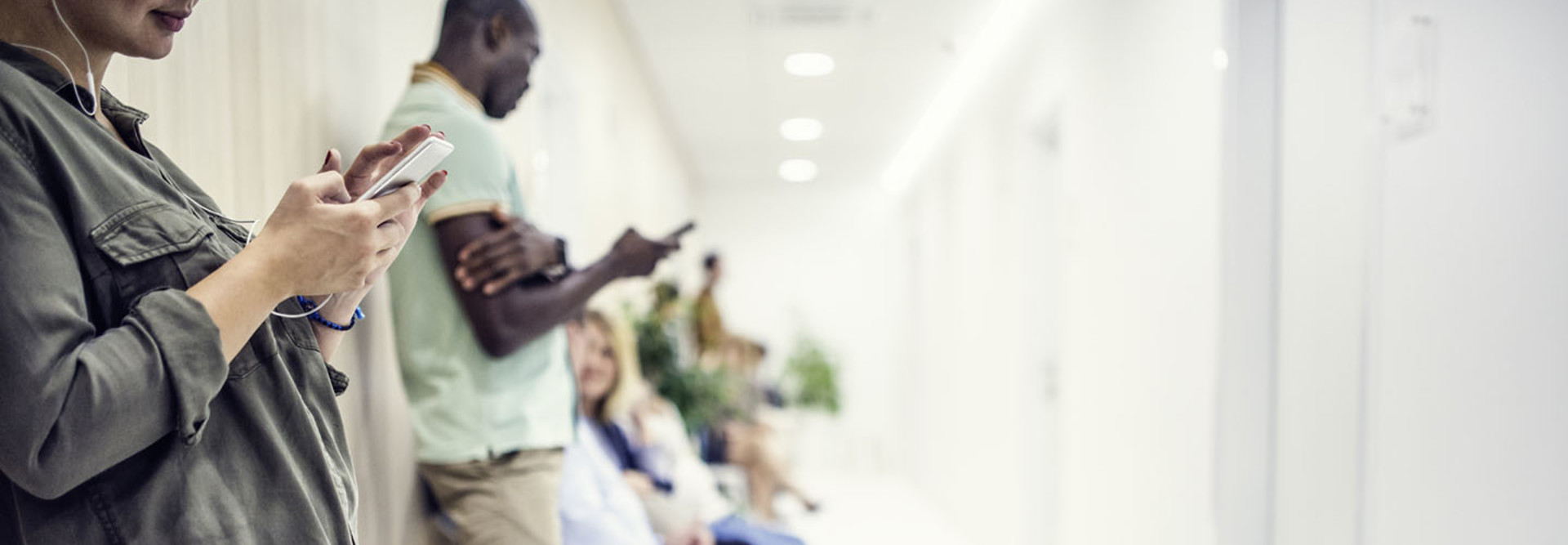 Patients using mobile phone in waiting room of clinic.