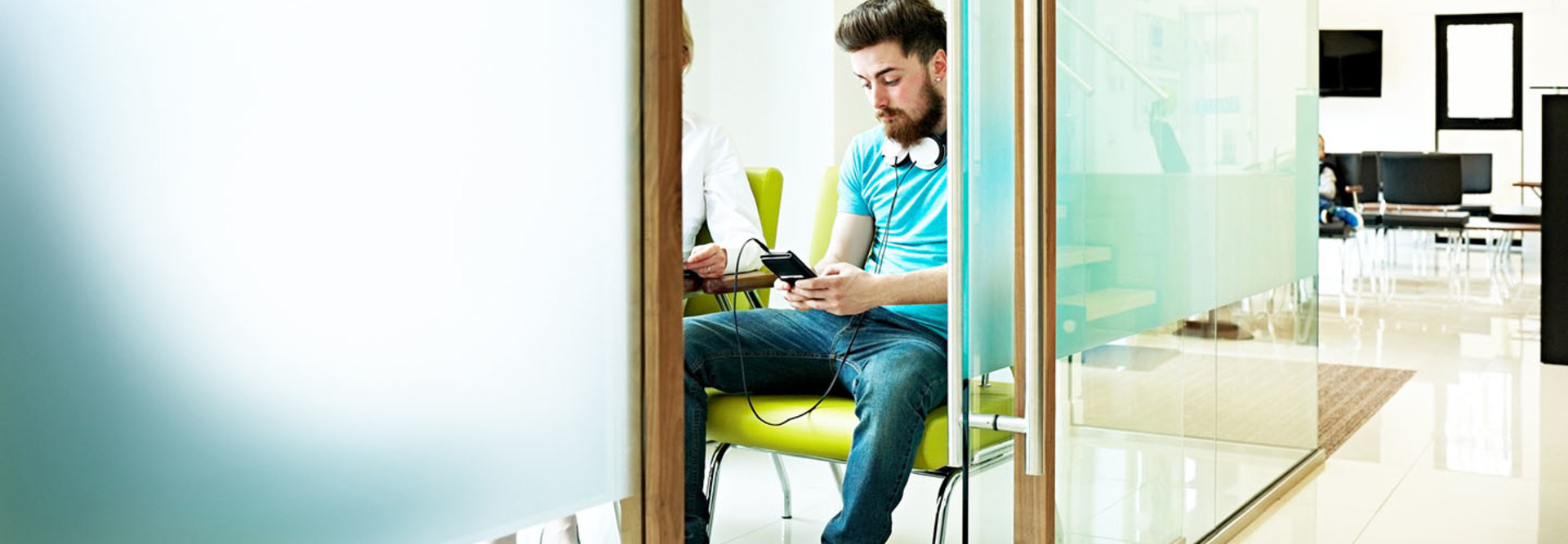 Young man sitting in waiting room at dental clinic using mobile phone