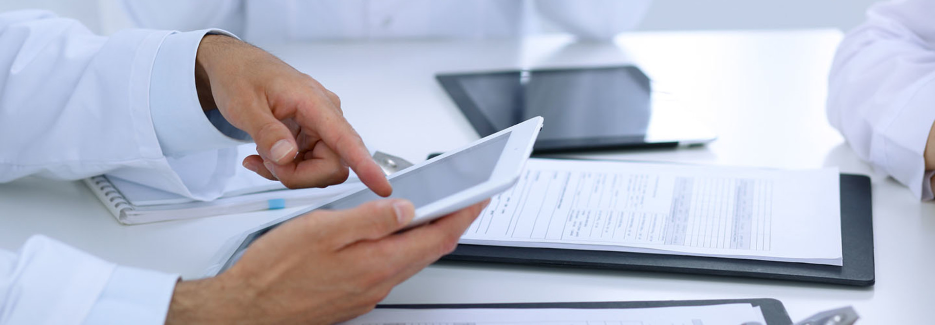 Group of doctors at medical meeting. Close up of physician using touch pad or tablet computer