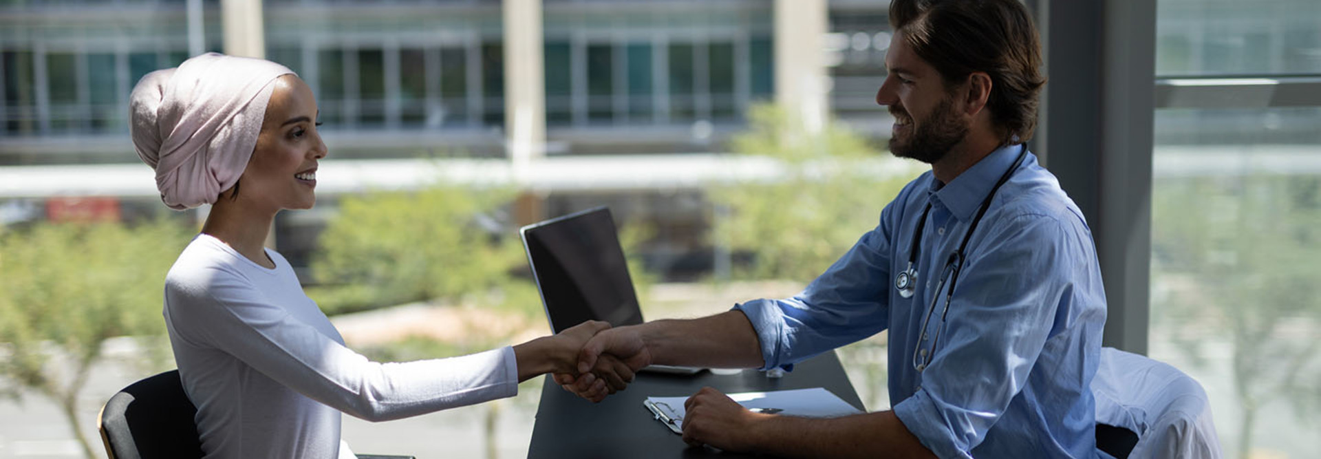 Disabled mixed-race woman shaking hands with Caucasian male doctor