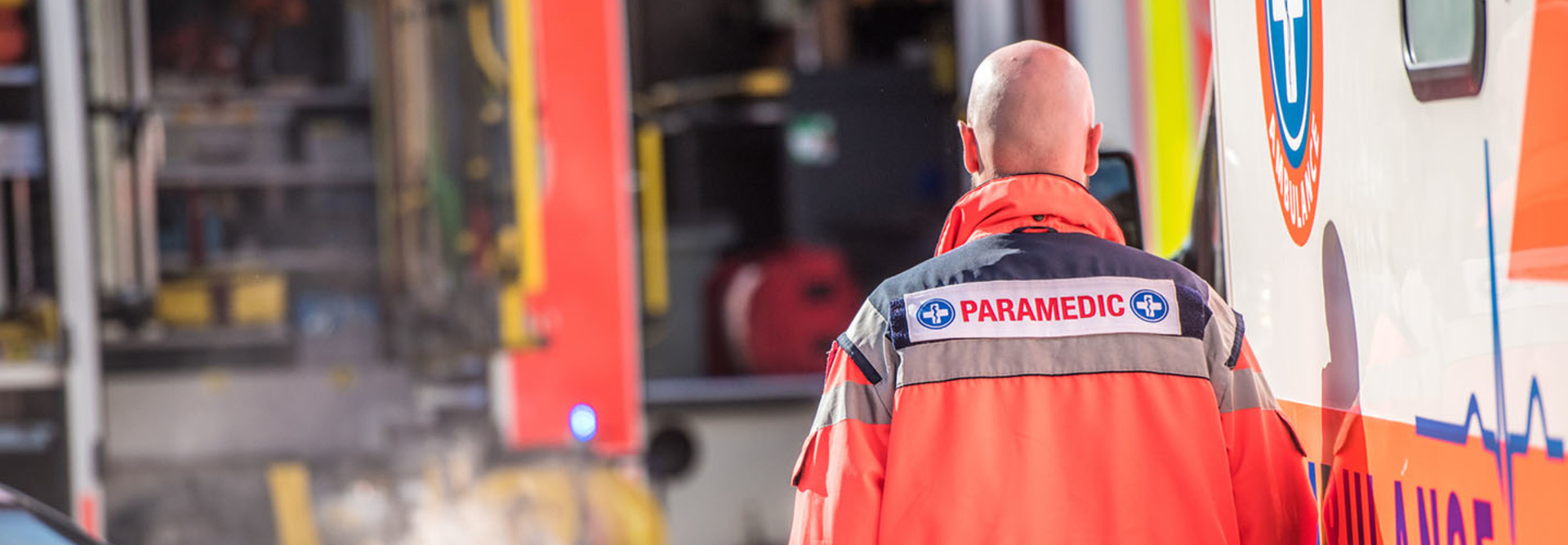 Rear view of male paramedic walking outside ambulance.