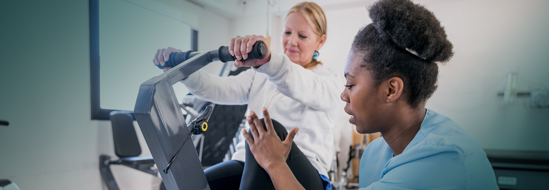 Nurse helping woman on rehab bike