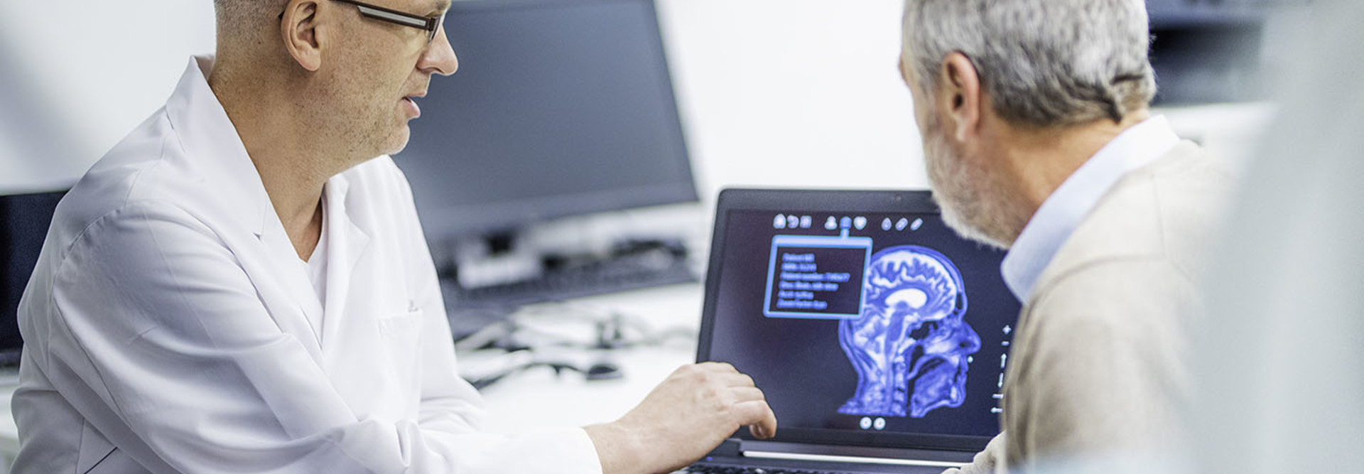 Doctor showing patient his brain scans on a computer after a successful brain tumour surgery.