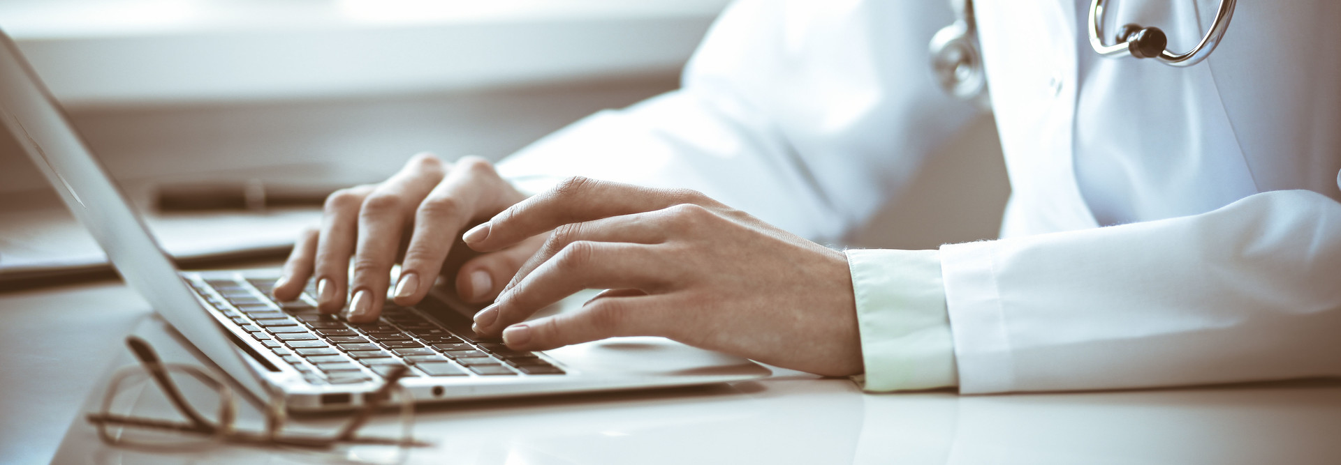 Doctor types on laptop