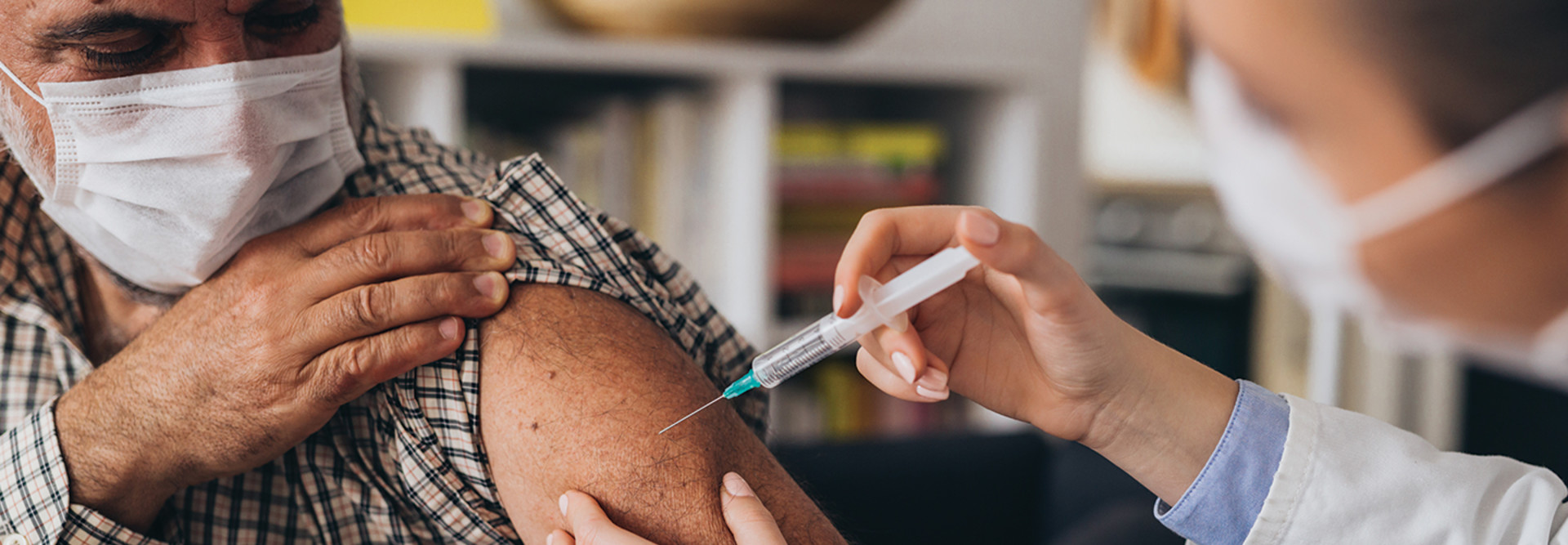 Health worker injecting a vaccine into a patient's arm.