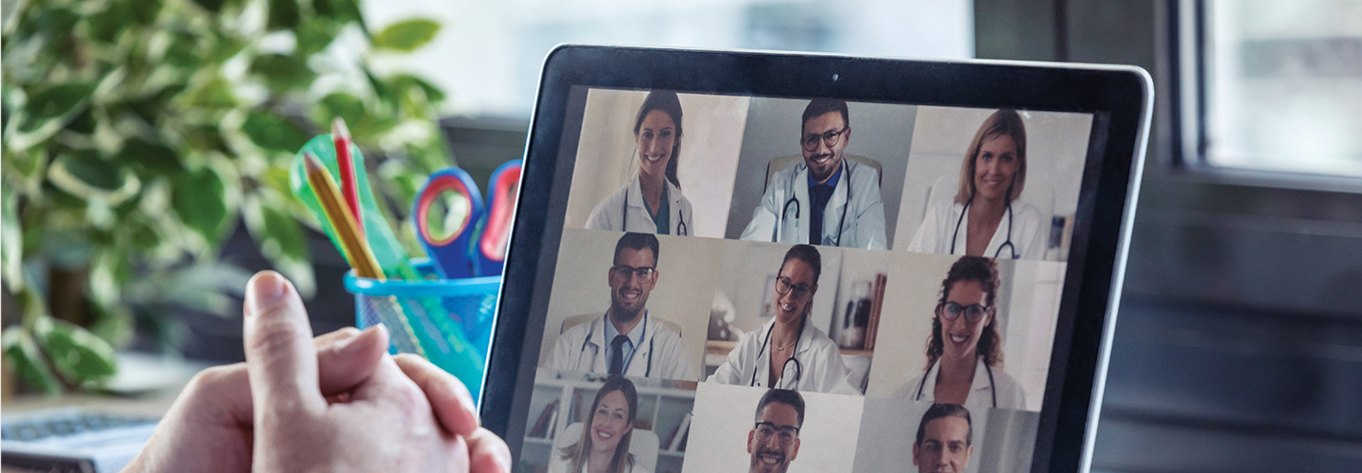 Male doctor having video conference on laptop with his colleagues at home.