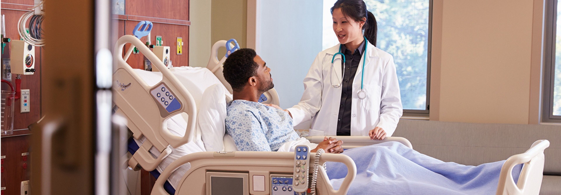 doctor checks on patient in hospital bed
