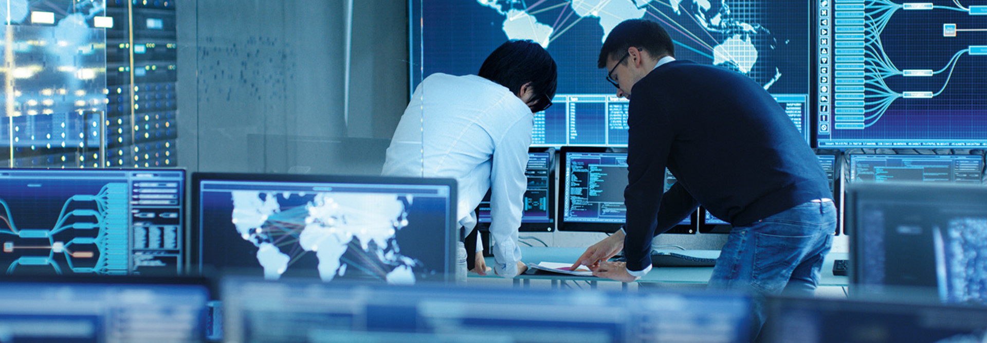 two men on cybersecurity team look at documents surrounded by computers