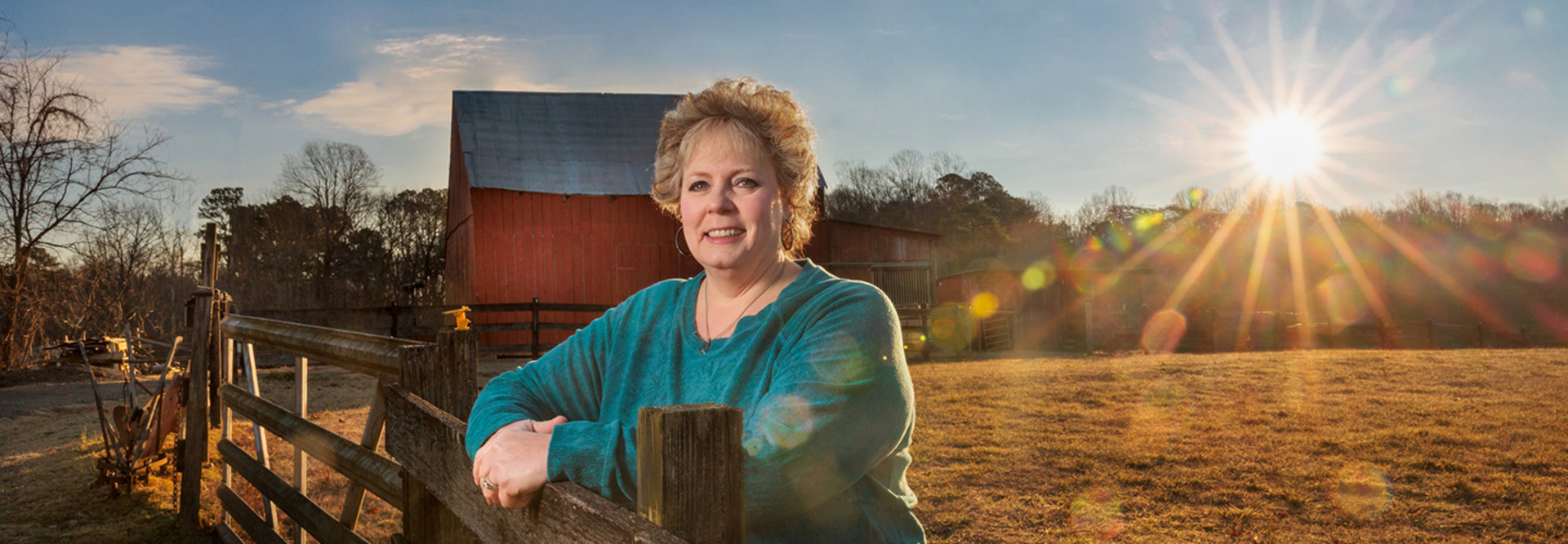 Melissa Hall on farm with barn and sunset in the background