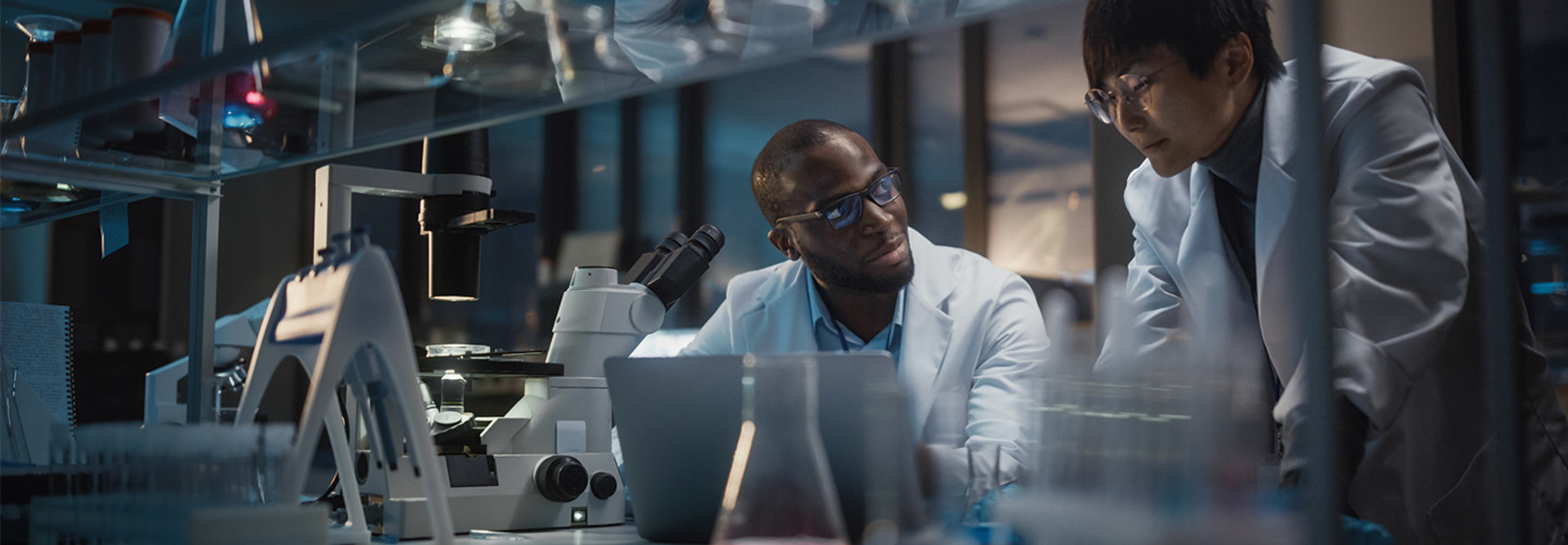 two scientists look at data on laptop in a lab