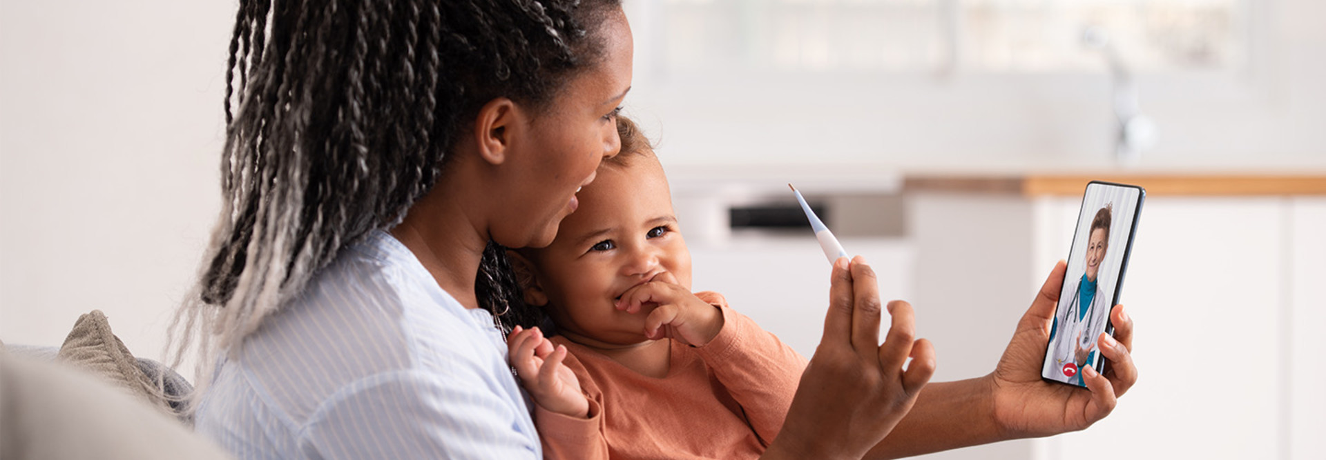 mother takes baby's temperature on telehealth call with doctor