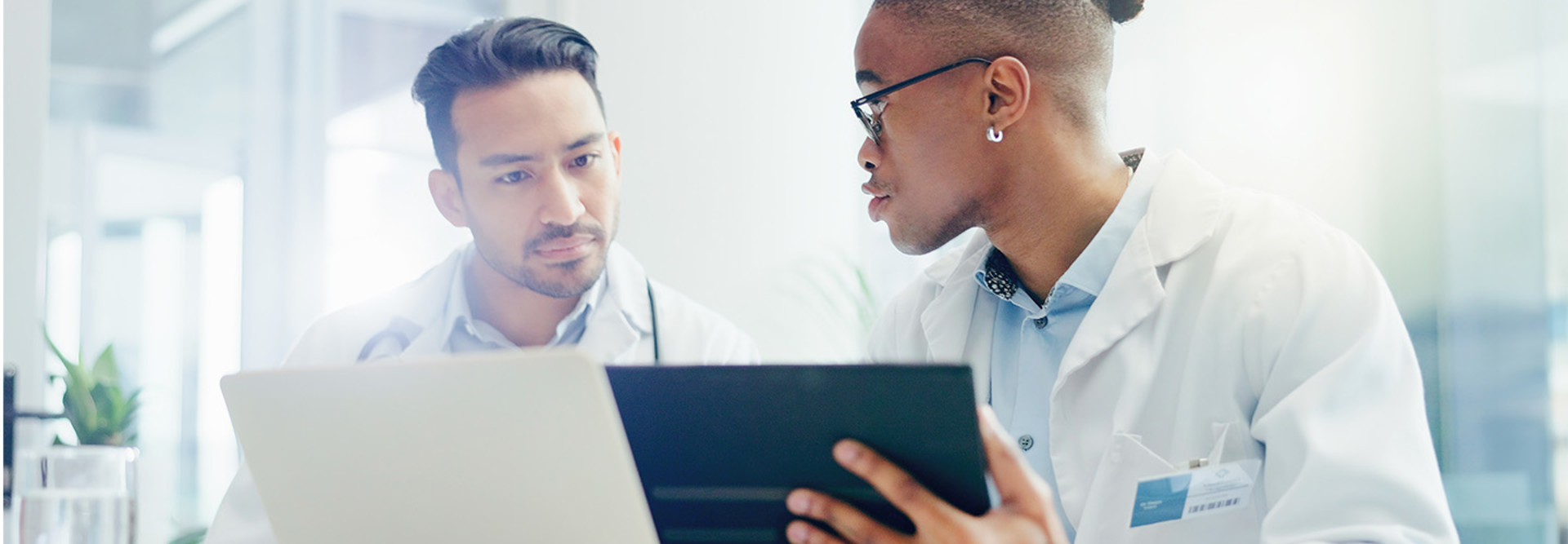 two doctors discuss treatment plans over laptop and tablet