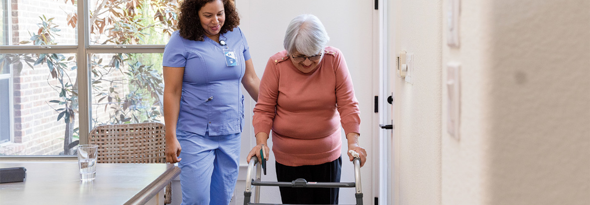 nurse helps patient with walker at home