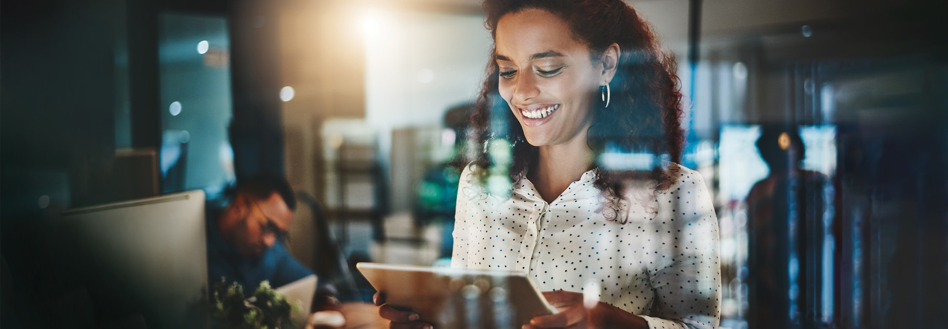 smiling woman looks at tablet in office