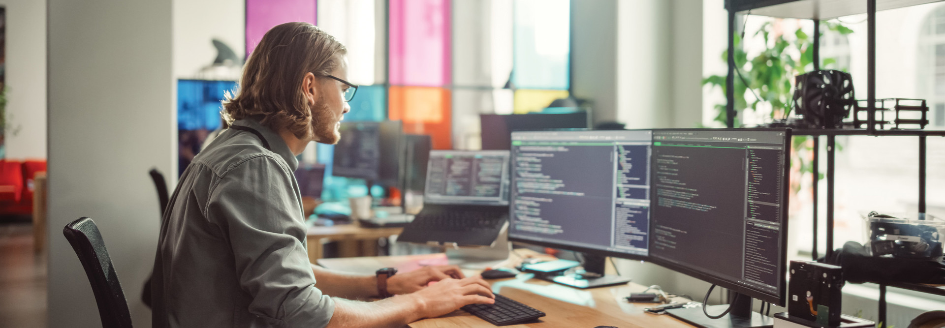 IT employee looks at code on two monitors