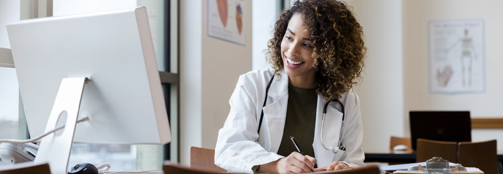 Doctor writing information from computer