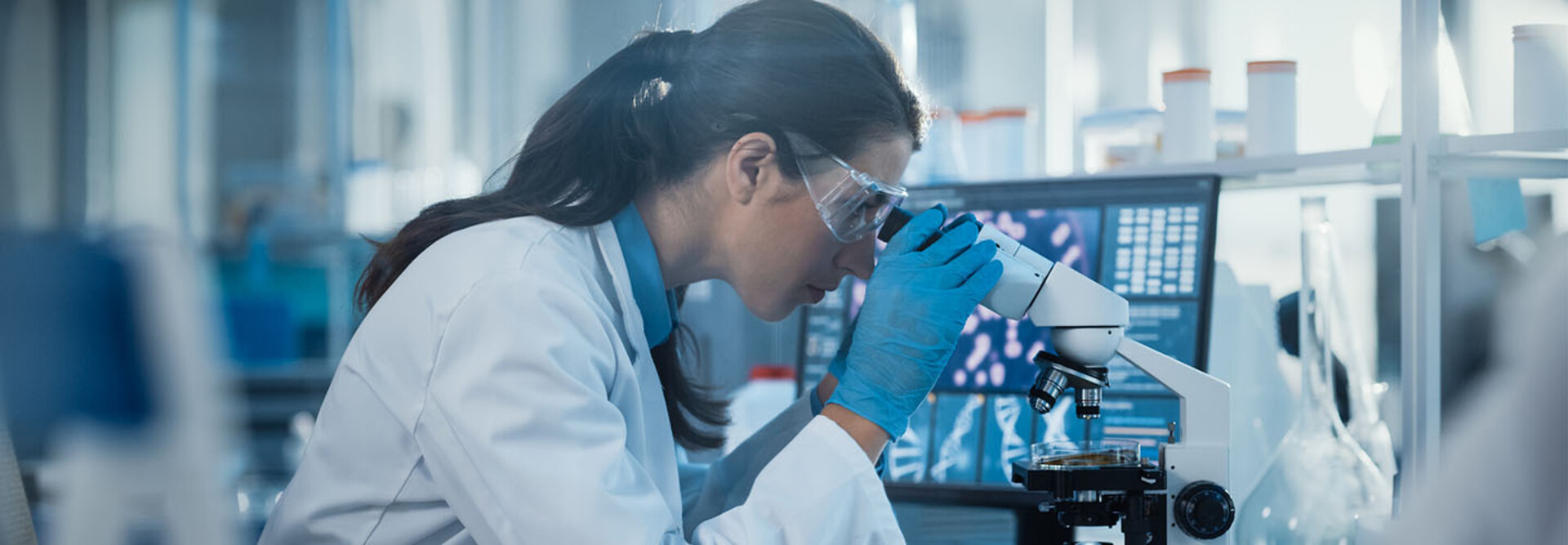 scientist looks through microscope in lab
