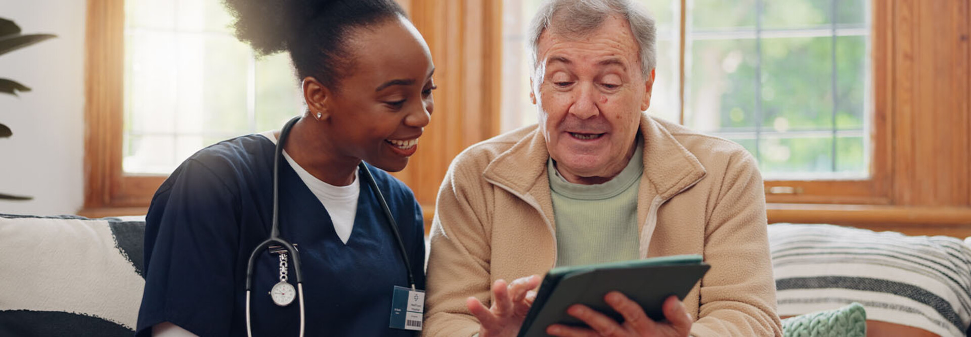 nurse and senior laugh while looking at tablet