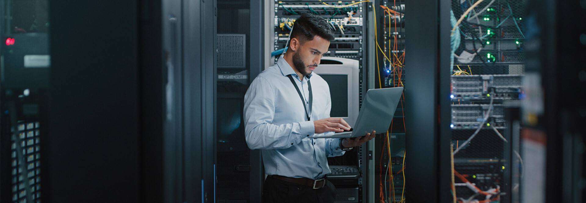 man on laptop in server room