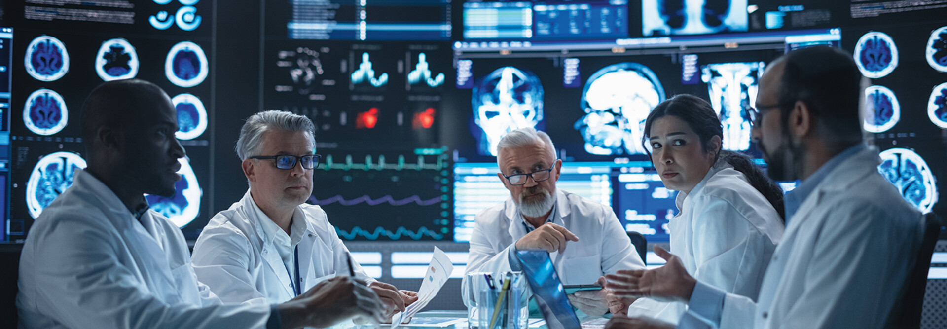 group of doctors talk amid large screens