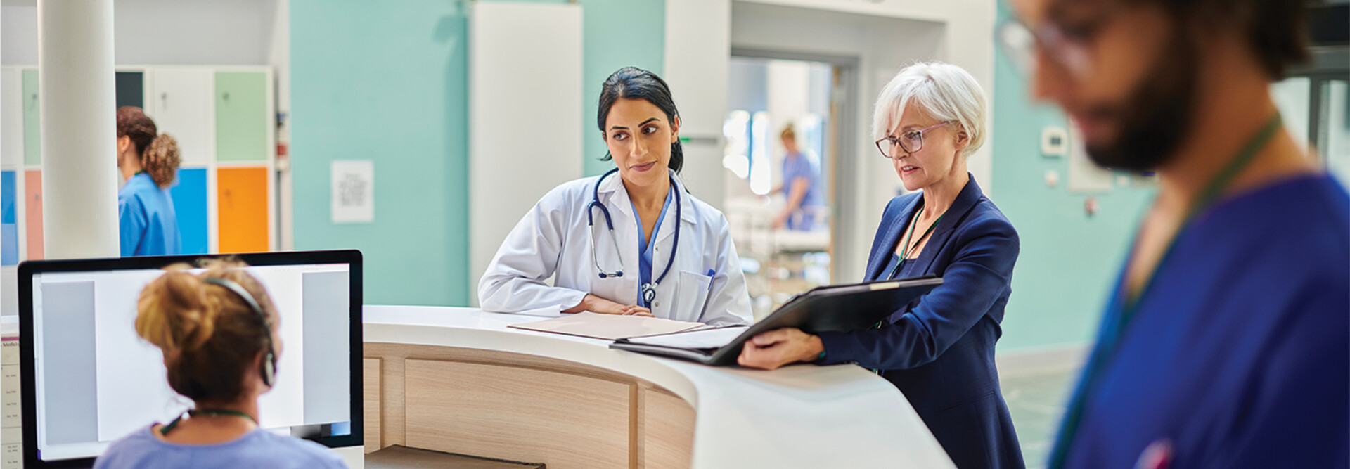 clinicians and administrators collaborate at hospital desk