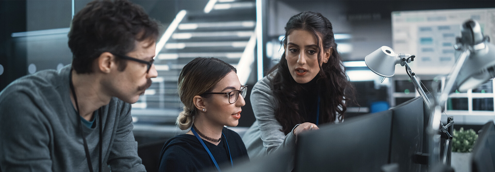 cybersecurity team members talk in front of monitors
