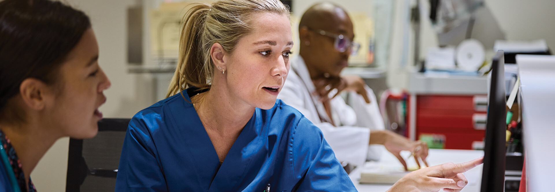 nurses talk in front of desktop computer