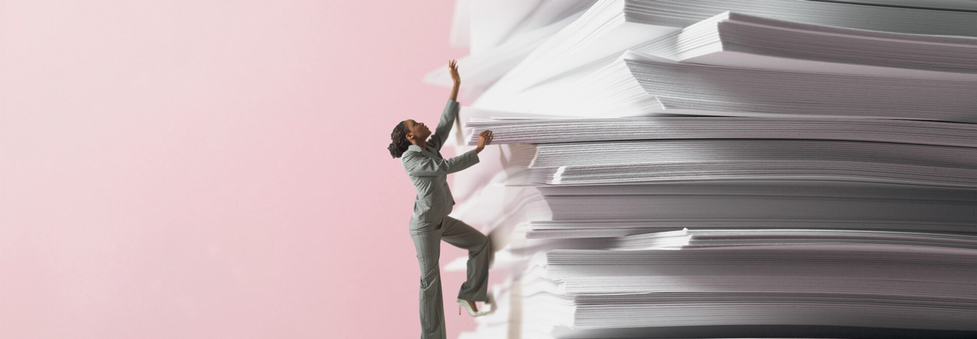 miniature woman climbs up stack of papers