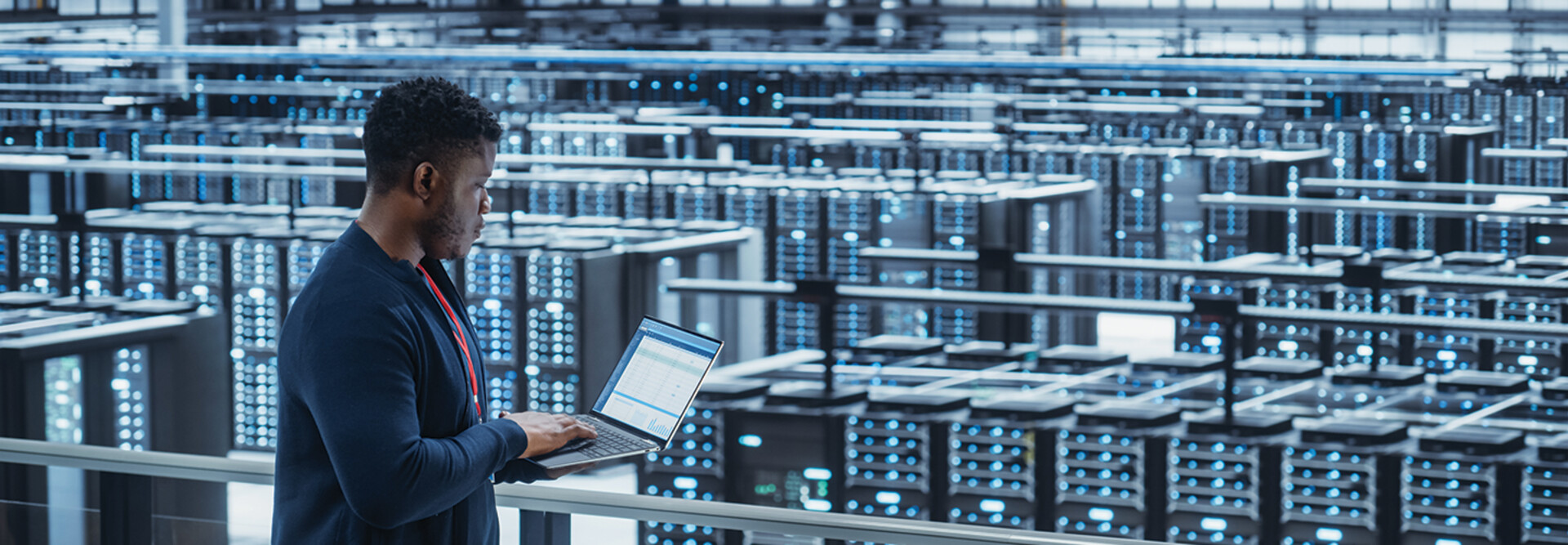 engineer with laptop overlooking data center