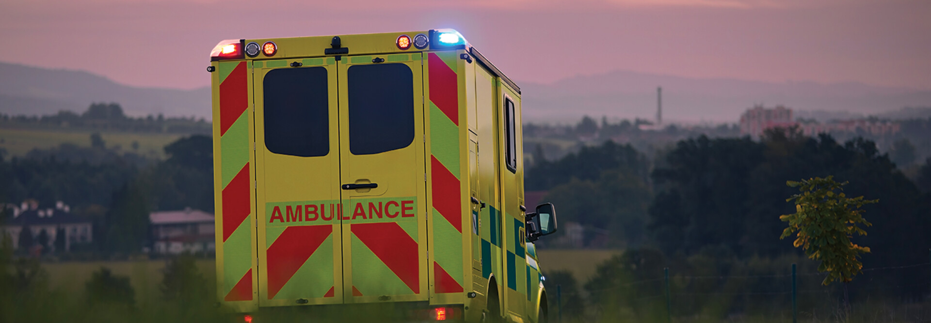 ambulance driving down country road at sunset