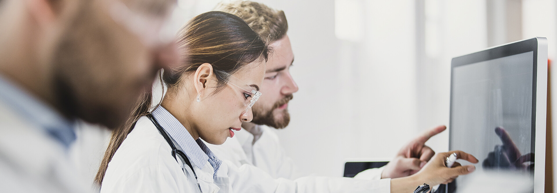 medical researchers look at data on desktop monitor
