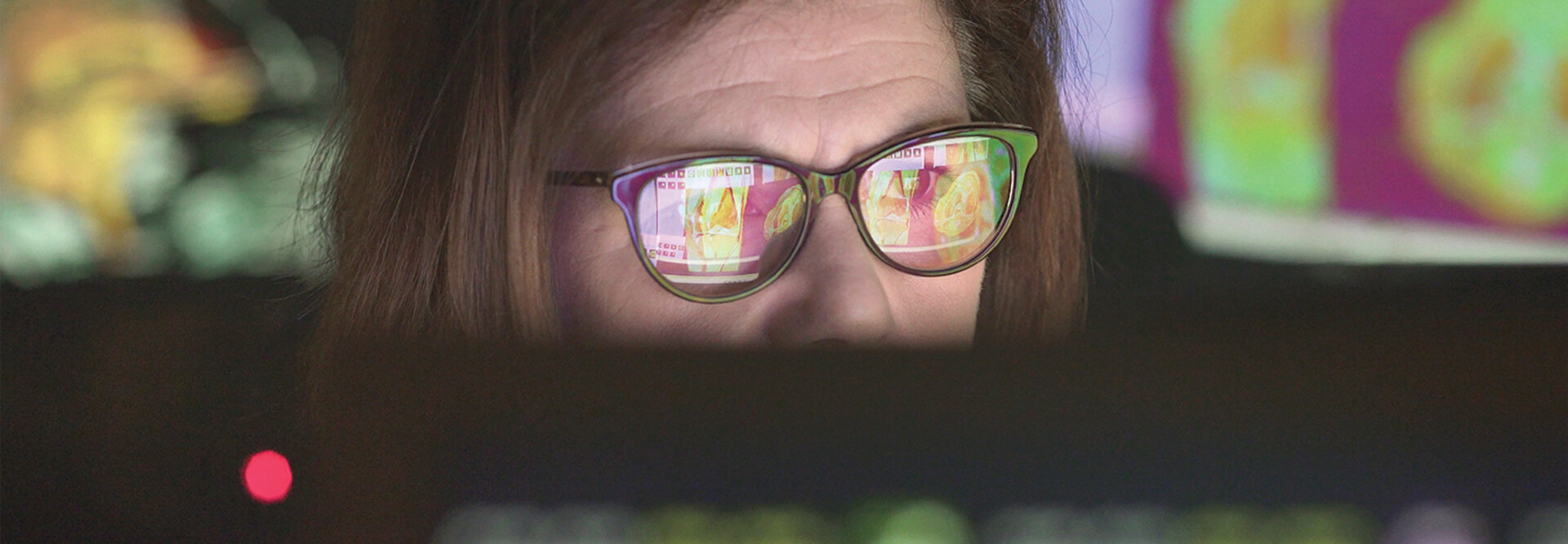 woman wearing glasses looking at healthcare data on screen
