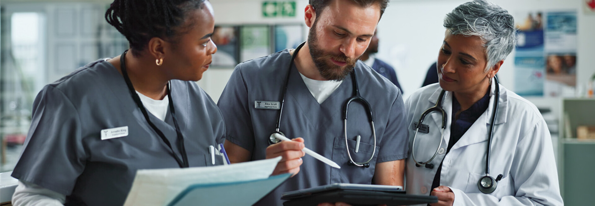 Team of clinicians talk over tablet