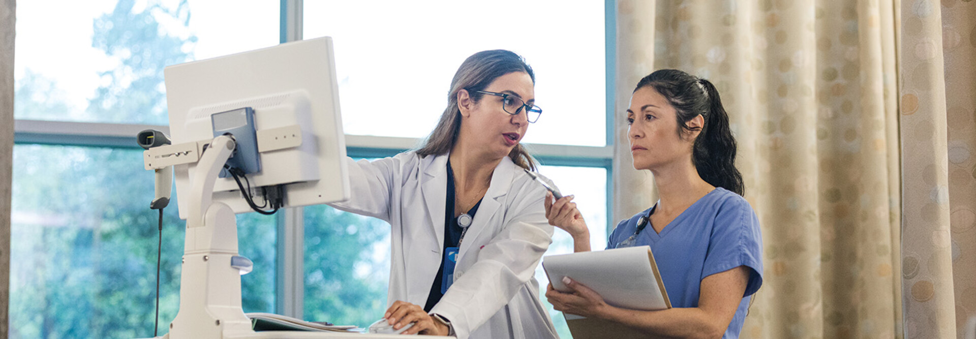 doctor shows intern AI features in an EHR on computer