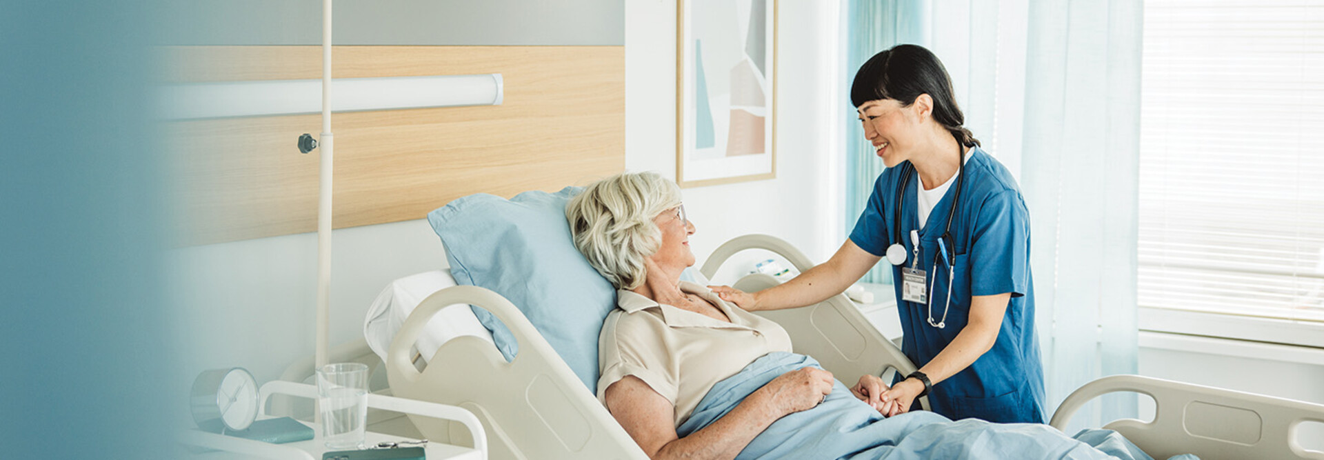 nurse cares for senior in hospital bed