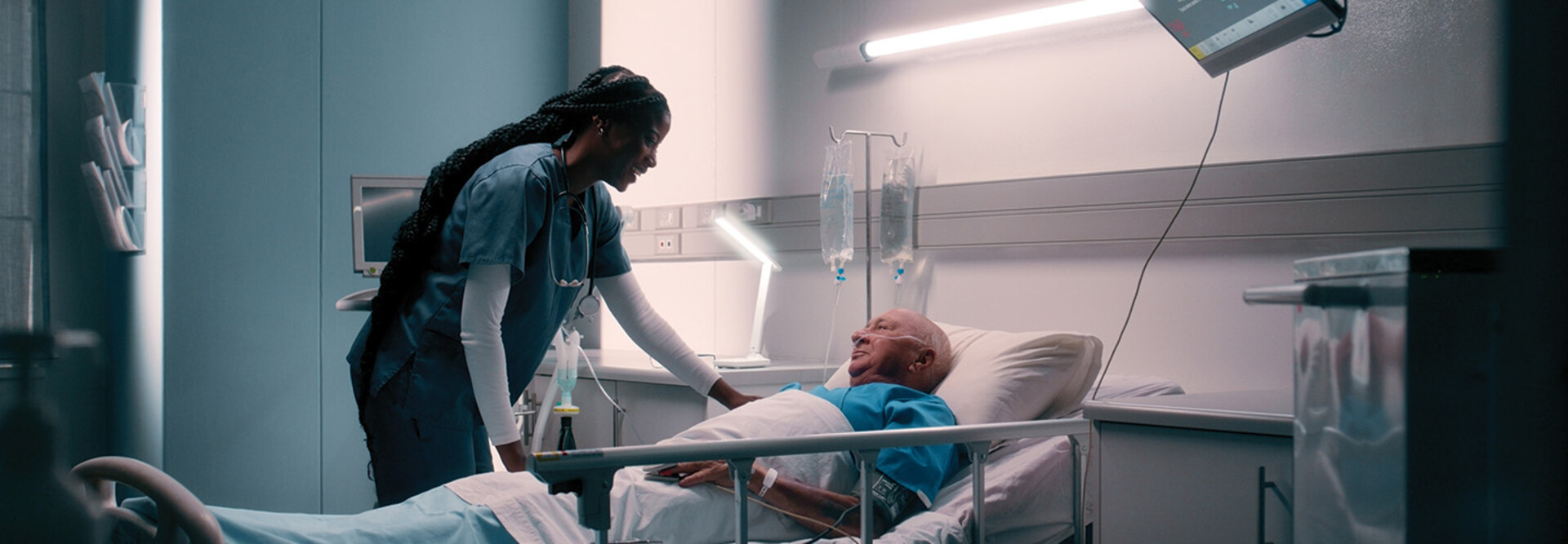 nurse talks to patient in hospital bed