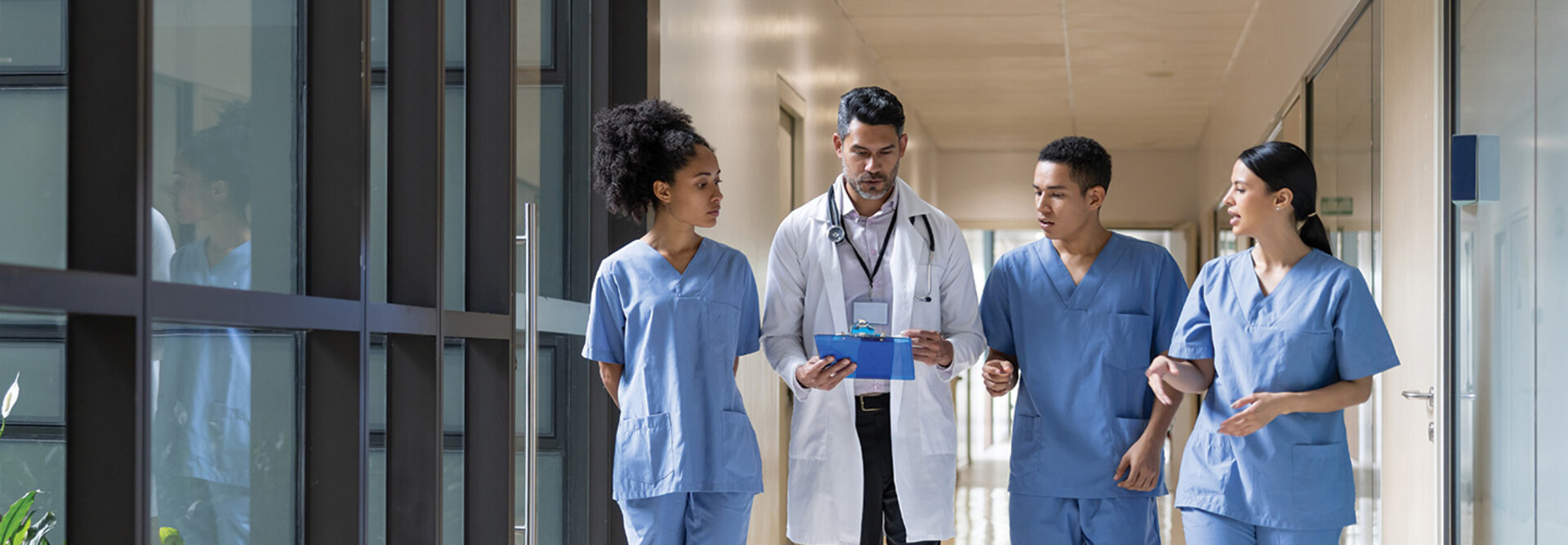 Doctor holding clipboard walks with medical students