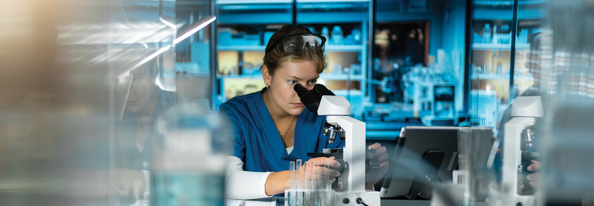 scientist looks through microscope in lab