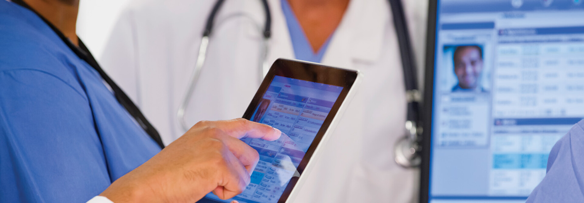 nurse and doctor look at EHR on tablet and monitor