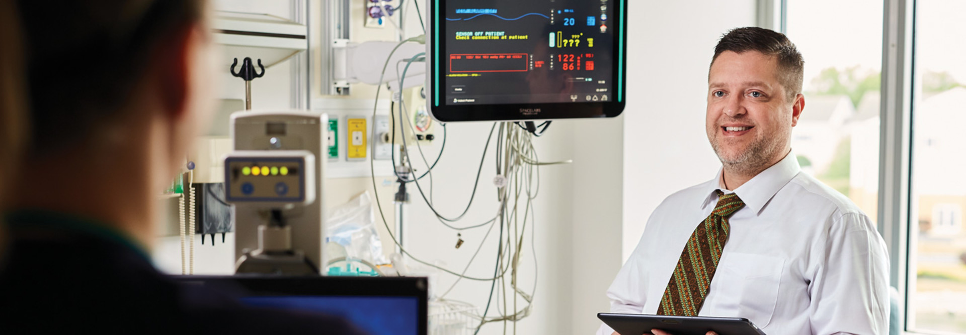 Doctor holding iPad speaks to patient 