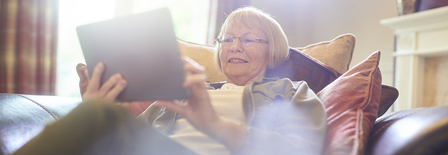 senior woman smiling as she uses her digital tablet