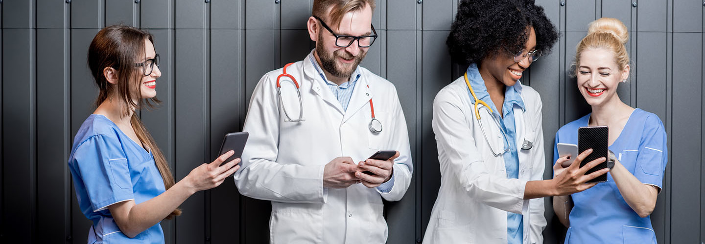 Multi ethnic group of medics standing with phones on the gray wall background