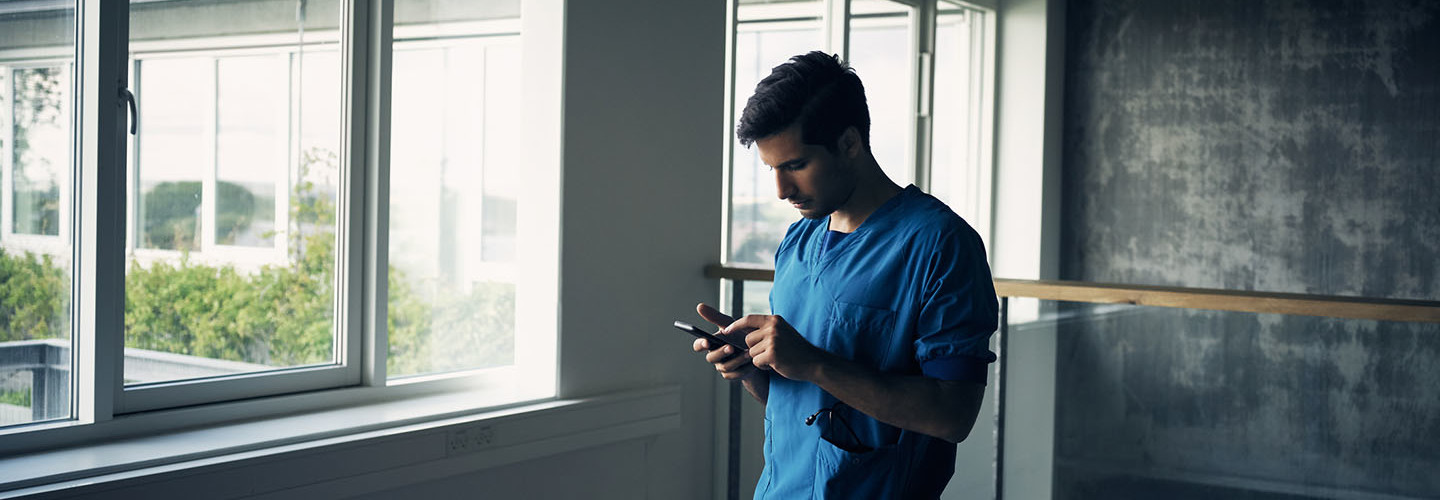 Shot of a focused young male doctor standing while being on his cellphone inside of a hospital